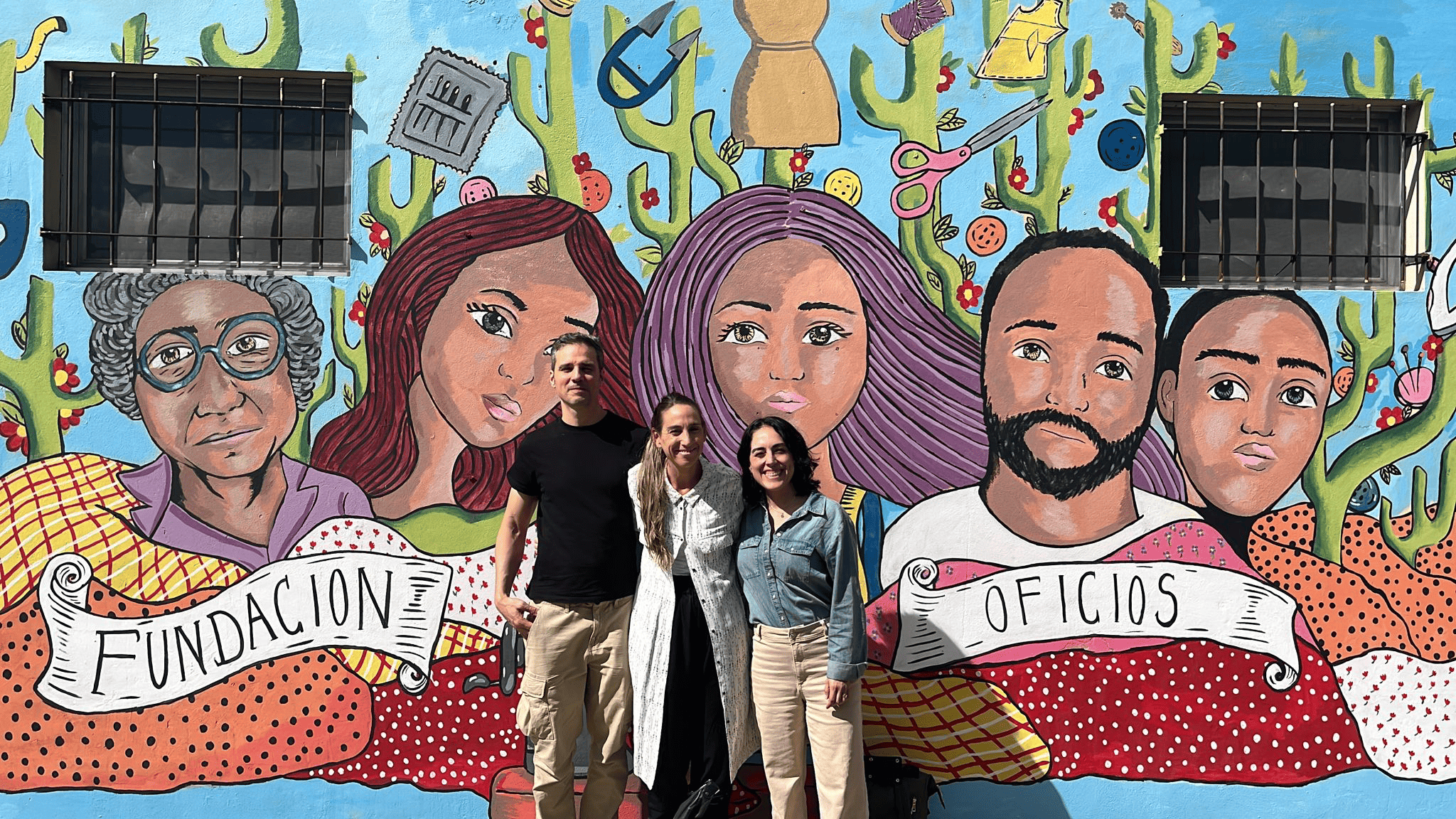 Three people standing in front of a mural